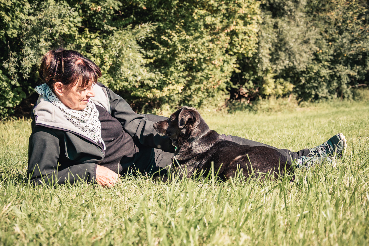 Zertifizierte Hundetrainerin Manuel Wagner zusammen mit ihrer Hündin Jessie auf einer Wiese